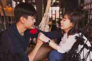 Free photo couple looking into each other's eyes and one with a rose in his mouth