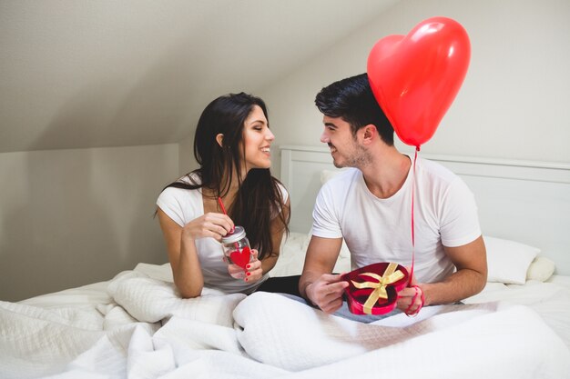 Couple looking into each other's eyes while the groom holds a gift and a balloon