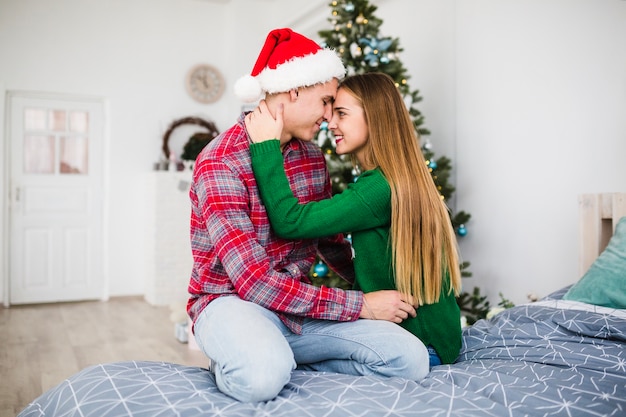 Couple looking into each others eyes on bed at christmas