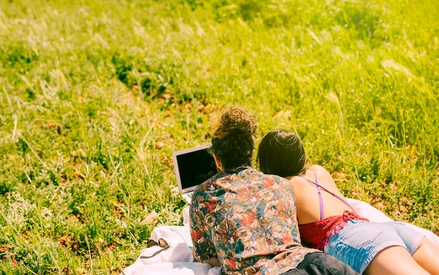 Free photo couple looking into laptop on meadow