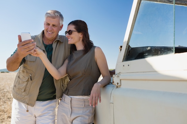 Couple looking into mobile phone by vehicle