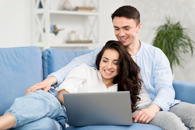Пара смотрит на ноутбук у себя дома на диване