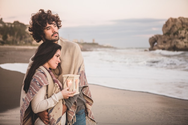 Couple looking at the sea while holding a candle