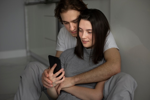 Coppia guardando smartphone mentre coccole