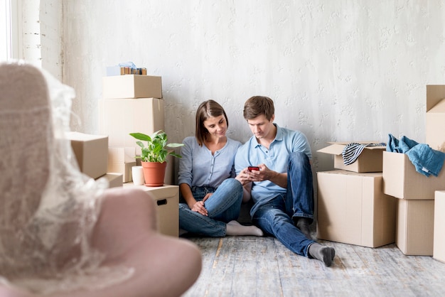 Couple looking at smartphone while packing to move house
