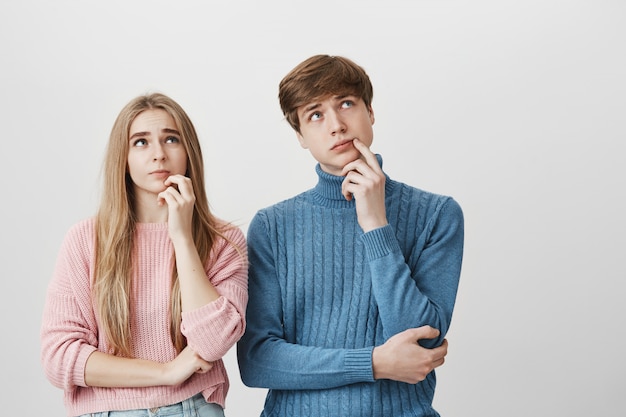 Couple looking up thoughtful. Blond girl and guy thinking, choosing