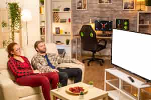 Free photo couple looking at white isolated tv screen late at night in living room.