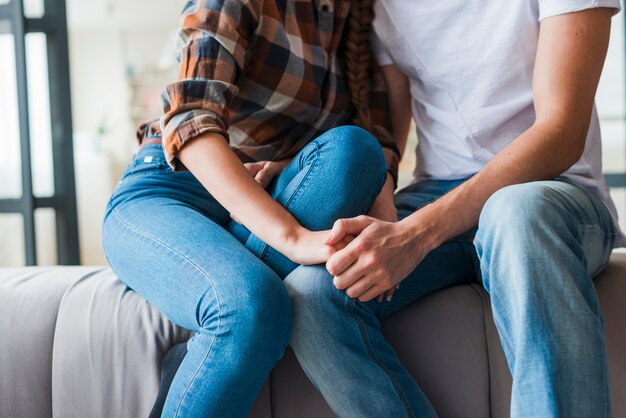 Couple in love holding hands on sofa 