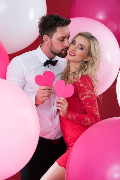 Влюбленная пара держит розовые сердечки из бумаги