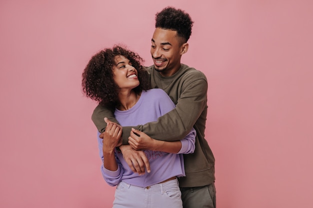 Couple in love looking at each other with love and smiling on pink wall