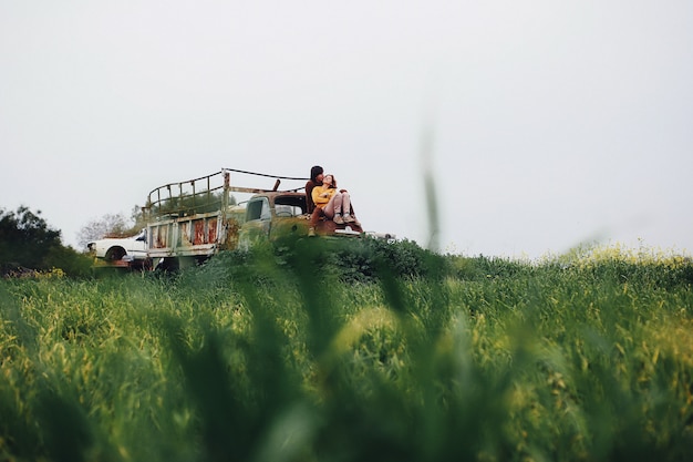 Couple in love sit on the abandoned truck and smile