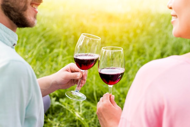 Couple in love toasting wineglasses sitting on grass