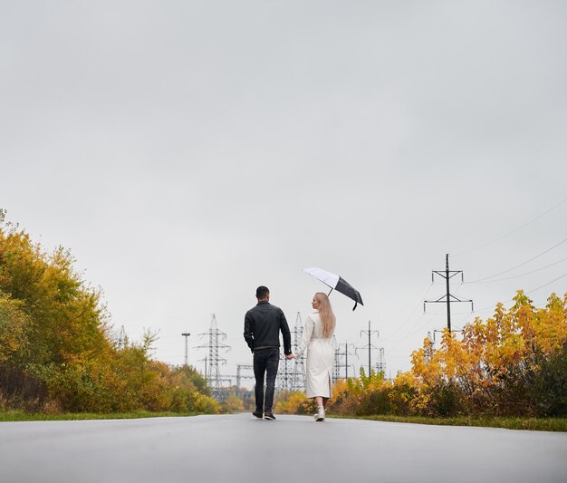 Couple in love walking on the road under cloudy sk