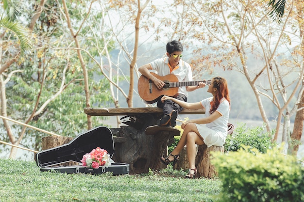 Couple in love with playing guitar at nature