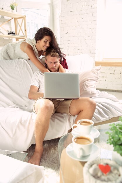 Couple of lovers at home relaxing together. Caucasian man and woman having weekend, looks tender and happy