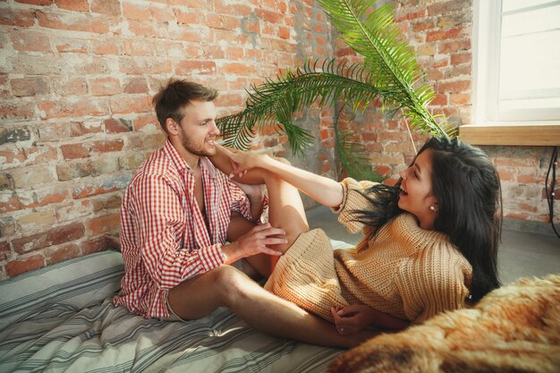 Couple of lovers at home relaxing together. Caucasian man and woman having weekend, looks tender and happy