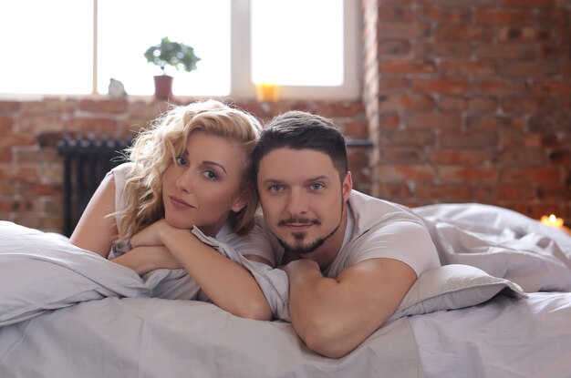 Couple lying on the bed and looking to the camera