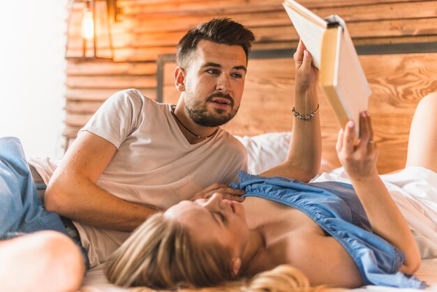 Couple lying on bed reading book