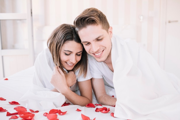 Couple lying on bed with rose petals