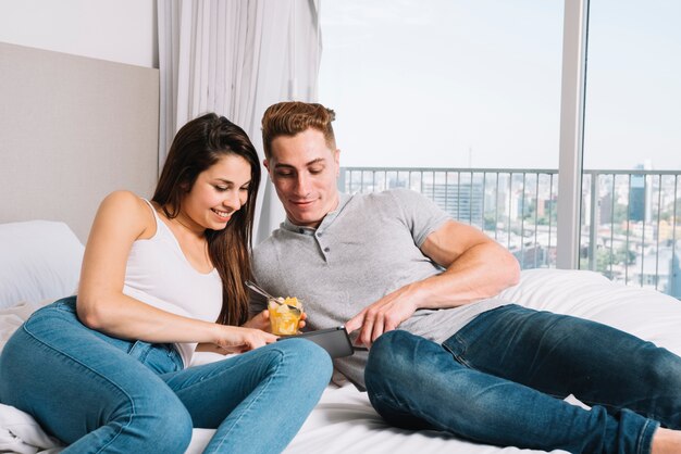 Couple lying on bed with smartphone 