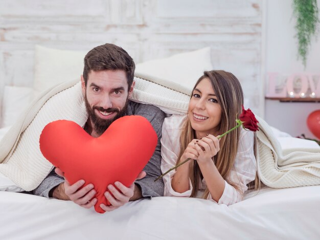 Couple lying on bed with soft red heart 