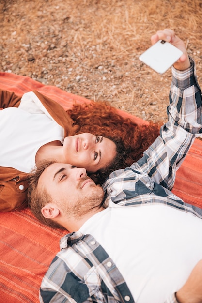 Coppie che si trovano sulla coperta che prende un selfie