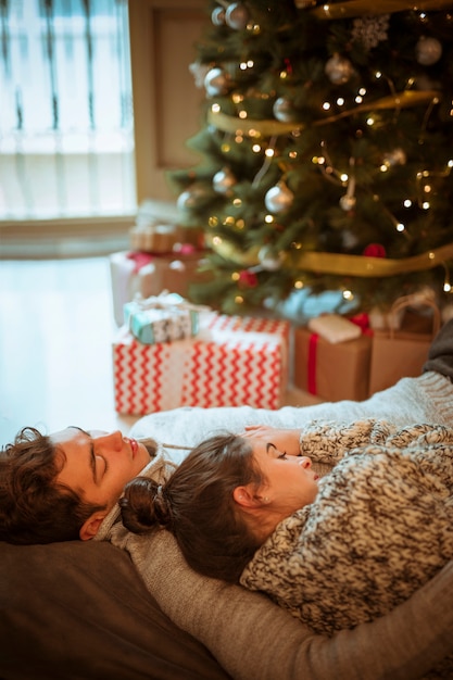 Free photo couple lying at christmas tree