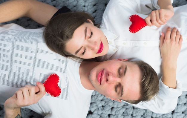 Free photo couple lying with small toy hearts