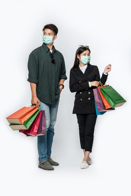 A couple of man and woman wearing masks and carried lots of paper bags to shop