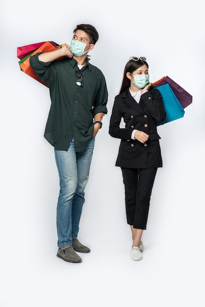 Пара мужчина и женщина в масках несли много бумажных пакетов в магазин