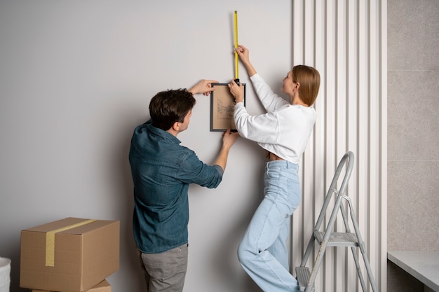 Free photo couple measuring the wall before hanging a frame