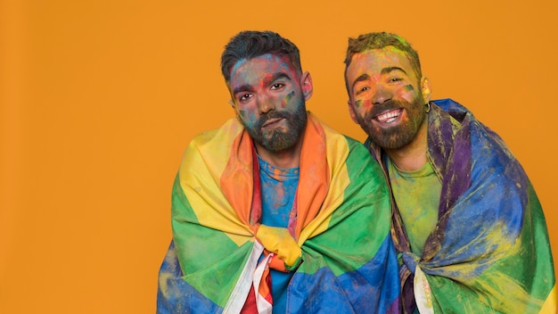 Бесплатное фото Пара гомосексуальных мужчин в художественной краске, покрытых флагом лгбт