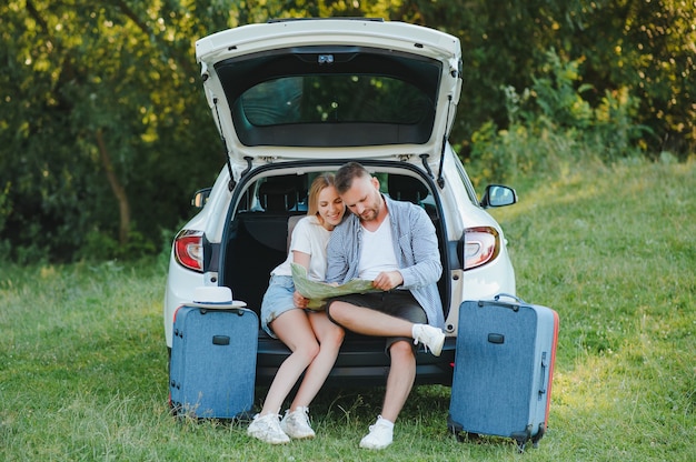 휴가 기간 동안 도로 근처의 자동차 해치백에 앉아 있는 여행자 커플.