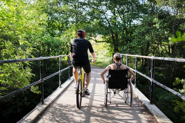 Пара на тренировке вместе на велосипеде и в инвалидной коляске