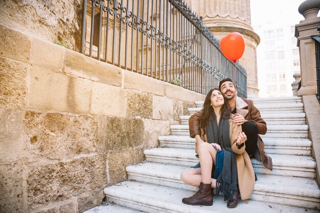 Бесплатное фото Пара на лестнице, глядя на воздушный шар