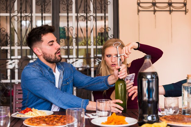 Couple opening alcohol bottle with opener