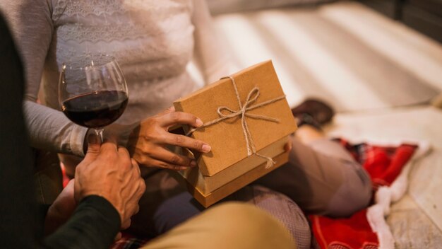 Couple opening gifts together with glass of wine