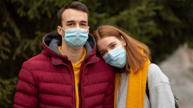 Пара на открытом воздухе вместе в медицинских масках