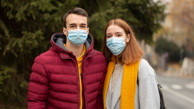 Free photo couple outdoors wearing medical masks