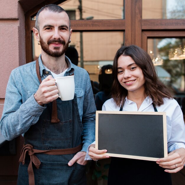 Couple outside coffee shop holding cup and blackboard