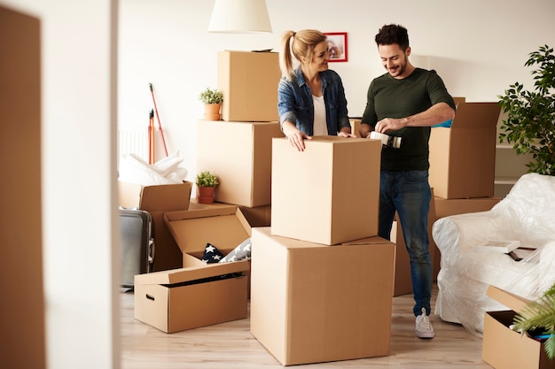 Couple packing stuff among plenty of cardboard boxes