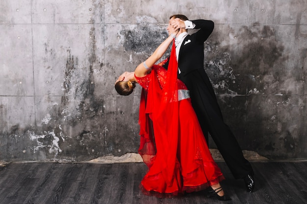 Free photo couple performing dance near gray wall