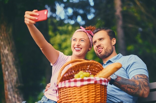 スマートフォンとインスタントメッセージングを使用して、都市公園でピクニックをしているカップル。