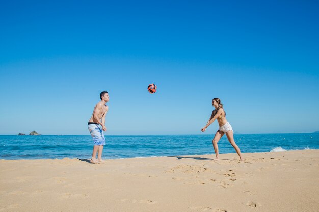 Пара играет в мяч на пляже