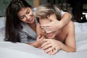 Free photo couple playing in bed, woman closing man eyes with hands