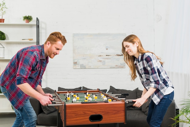 Couple playing football table soccer game at home