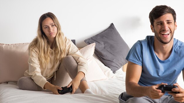 Пара играет в видеоигру в постели, средний план