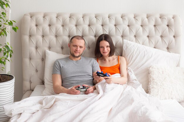 Couple playing videogames in bed