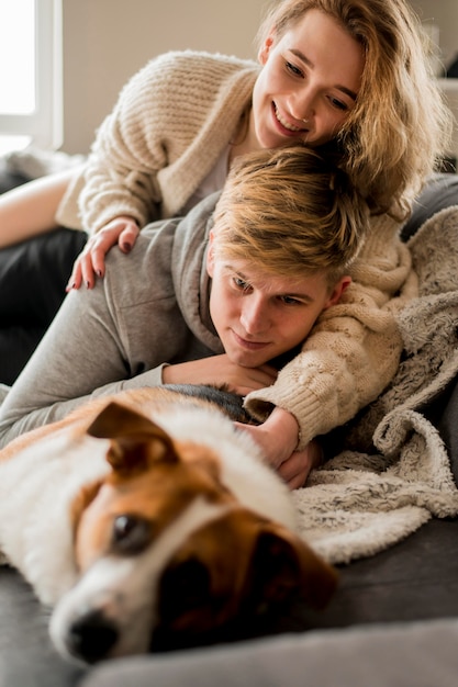 Coppia giocando con il cane nel letto