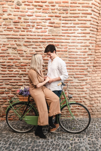 Couple posing against brick wall with bicycle